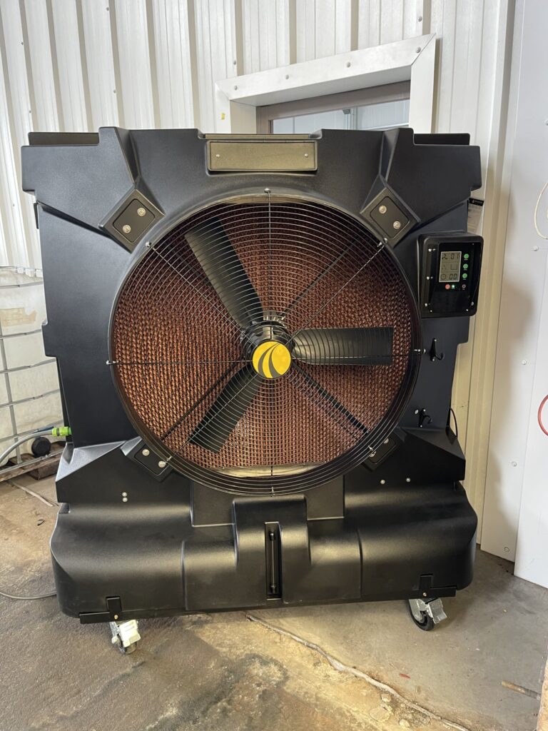 Large industrial fan with control panel, placed indoors on a concrete floor.