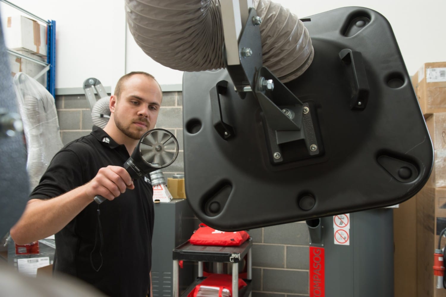 Man using a tool to inspect industrial equipment in a workshop.